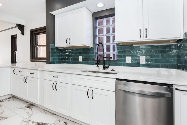 kitchen featuring tasteful backsplash, stainless steel dishwasher, sink, white cabinetry, and light stone counters