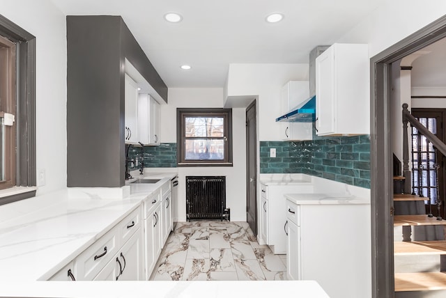 kitchen featuring white cabinetry, decorative backsplash, light stone counters, and sink