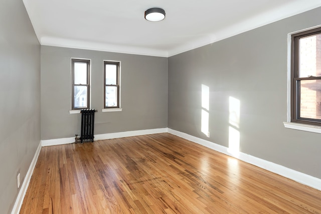 unfurnished room with plenty of natural light, ornamental molding, hardwood / wood-style floors, and radiator heating unit