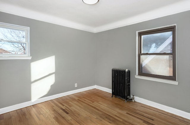 spare room with wood-type flooring, radiator heating unit, and crown molding