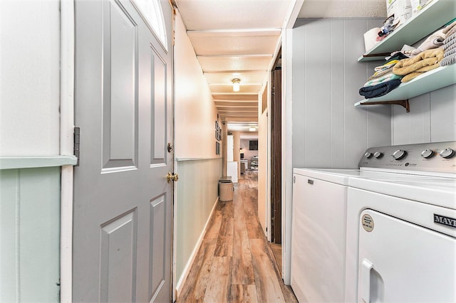 laundry area featuring washing machine and clothes dryer and light hardwood / wood-style floors