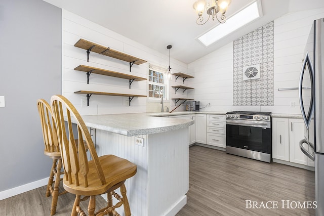 kitchen with white cabinetry, pendant lighting, kitchen peninsula, a breakfast bar, and appliances with stainless steel finishes