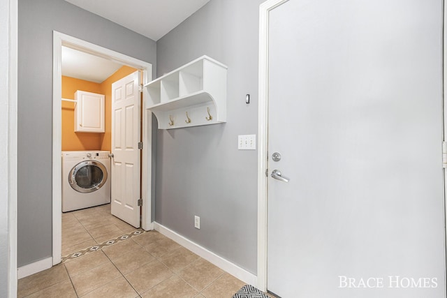 washroom with washer / dryer, light tile patterned floors, and cabinets