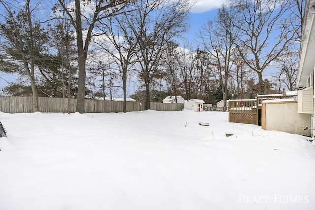 snowy yard with a deck and a shed