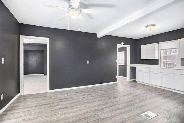 unfurnished living room featuring light hardwood / wood-style floors, ceiling fan, and beam ceiling