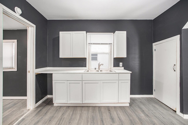 kitchen with sink, white cabinetry, and light wood-type flooring