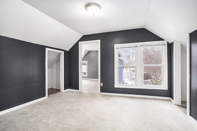 additional living space featuring vaulted ceiling and light colored carpet