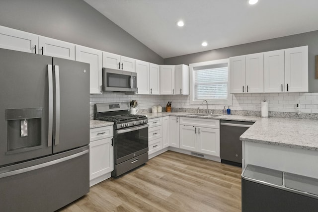 kitchen featuring vaulted ceiling, appliances with stainless steel finishes, sink, and white cabinetry