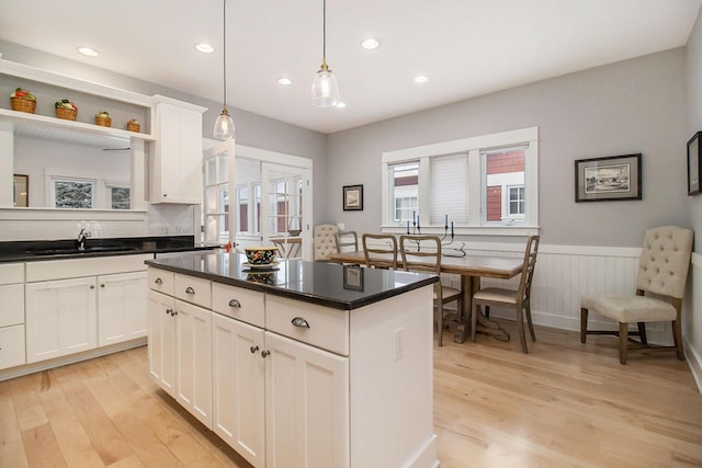 5 Georgia Ct, Pentwater, MI 49449 - kitchen featuring white cabinets, a wainscoted wall, a center island, light wood-type flooring, and a sink