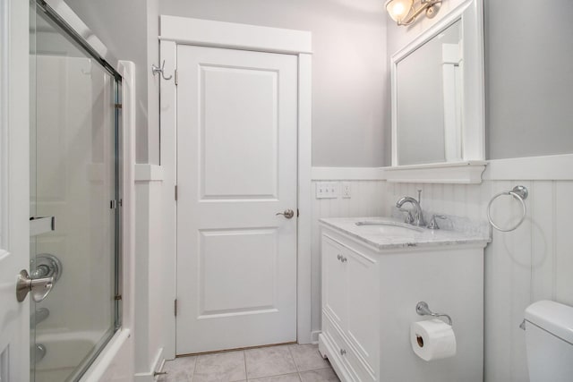 5 Georgia Ct, Pentwater, MI 49449 - full bath featuring toilet, bath / shower combo with glass door, vanity, wainscoting, and tile patterned floors