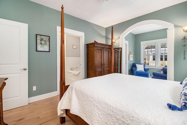 5 Georgia Ct, Pentwater, MI 49449 - bedroom featuring arched walkways, ensuite bathroom, light wood-style floors, ceiling fan, and baseboards