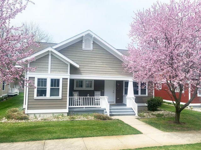 bungalow-style house featuring covered porch and a front lawn