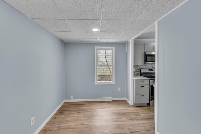 empty room with light hardwood / wood-style floors and a paneled ceiling