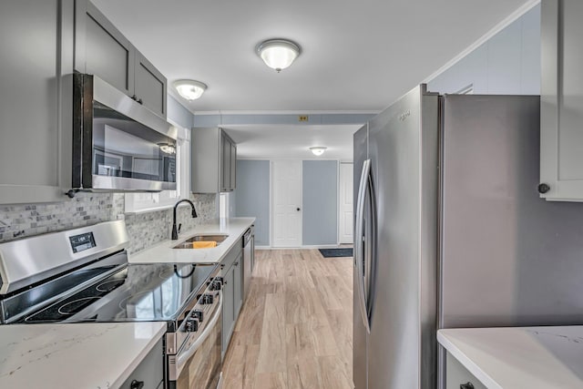 kitchen featuring light stone countertops, light hardwood / wood-style flooring, gray cabinets, appliances with stainless steel finishes, and sink