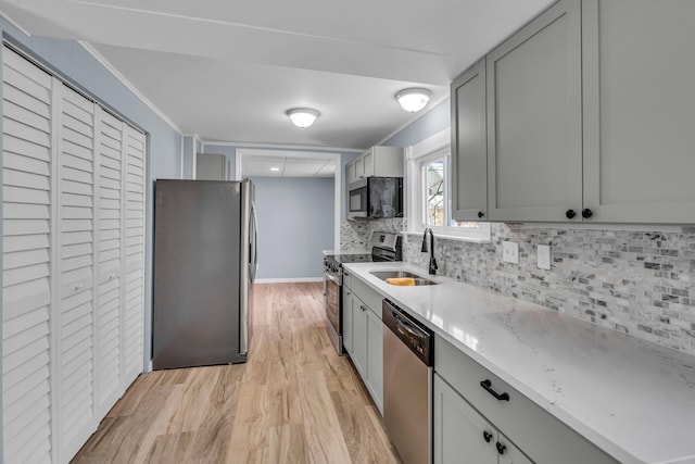 kitchen featuring appliances with stainless steel finishes, gray cabinets, backsplash, and sink