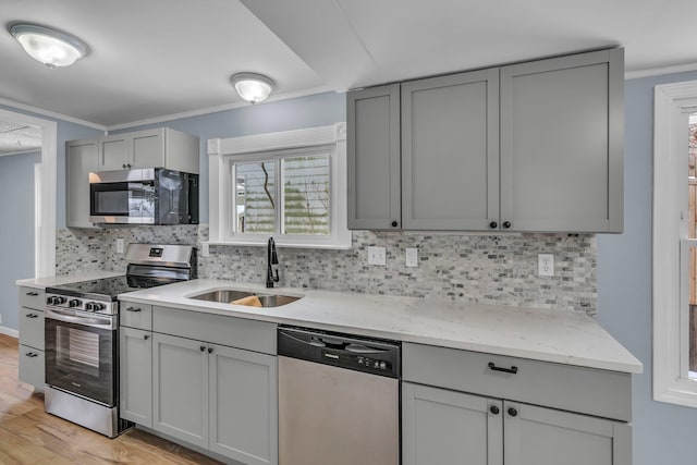 kitchen featuring stainless steel appliances, gray cabinets, backsplash, and sink