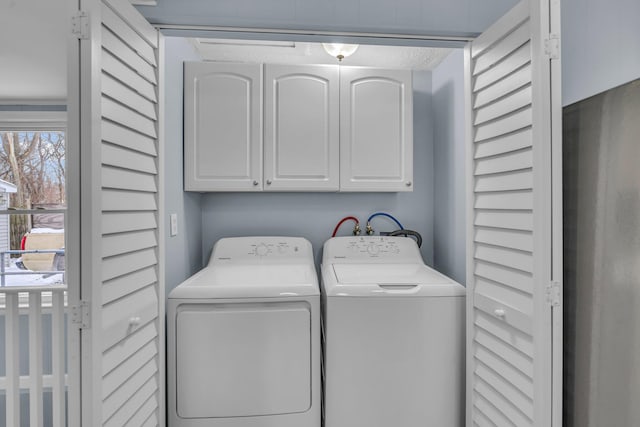 laundry area with separate washer and dryer and cabinets