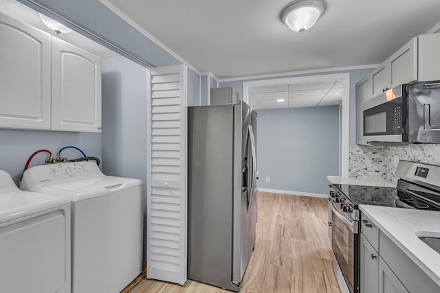 laundry room featuring ornamental molding, washing machine and clothes dryer, and light hardwood / wood-style flooring