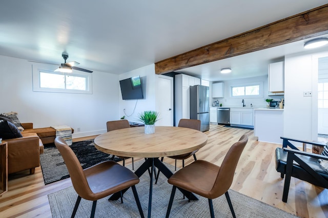 dining space featuring sink, ceiling fan, light hardwood / wood-style flooring, and beam ceiling