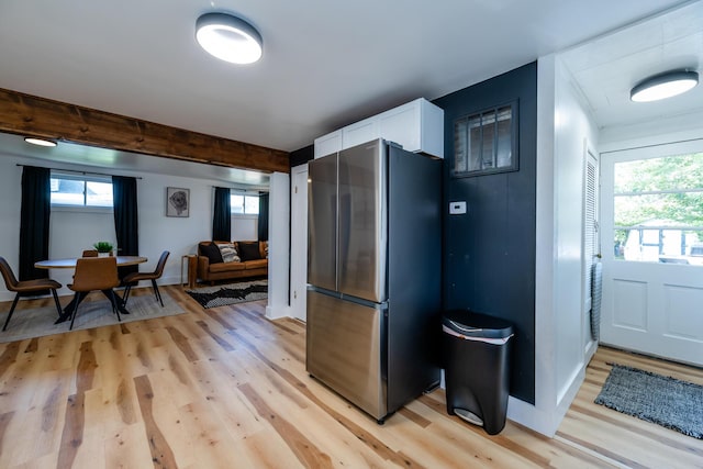 kitchen featuring stainless steel refrigerator, white cabinets, beam ceiling, and light hardwood / wood-style flooring