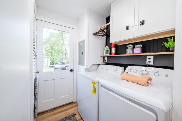 laundry area with electric panel, cabinets, light hardwood / wood-style flooring, and washer and clothes dryer