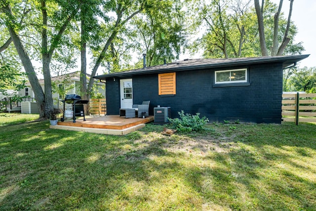 rear view of property featuring central AC, a yard, and a wooden deck