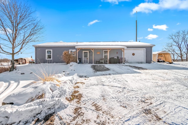 snow covered rear of property featuring a garage and covered porch