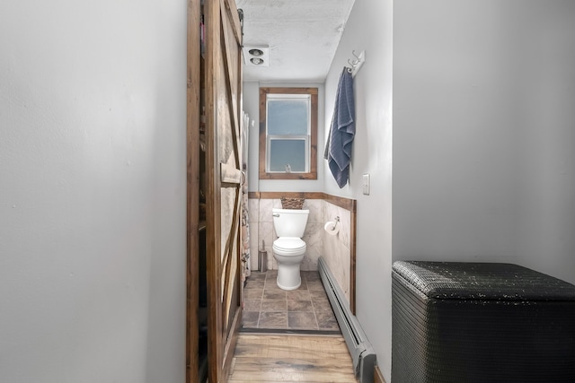 bathroom featuring toilet, a baseboard heating unit, and a textured ceiling