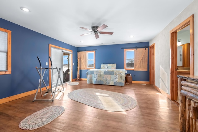 bedroom with ceiling fan, hardwood / wood-style flooring, and a barn door