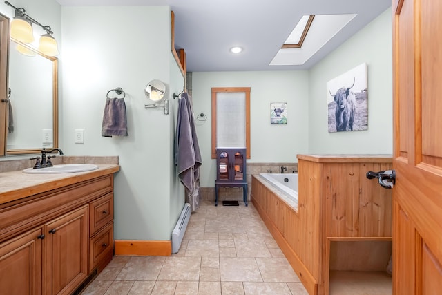 bathroom with tile patterned flooring, a baseboard heating unit, a skylight, tiled tub, and vanity