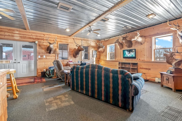 carpeted living room with ceiling fan and wooden walls