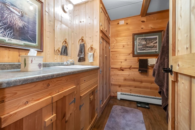 bathroom featuring hardwood / wood-style floors, a baseboard heating unit, wood walls, and vanity