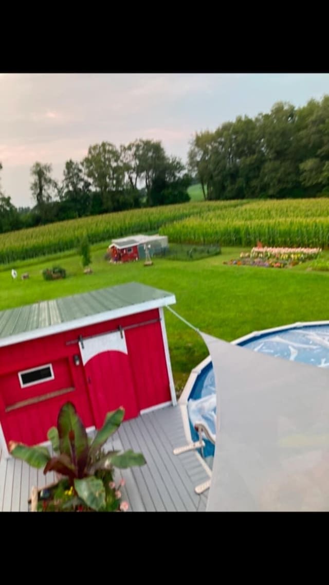 view of pool featuring a lawn and a rural view