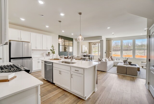 kitchen with appliances with stainless steel finishes, white cabinetry, a kitchen island with sink, and sink