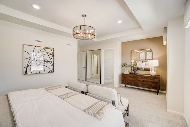 bedroom with a chandelier, a tray ceiling, and light carpet