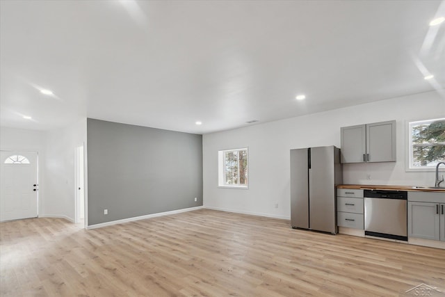 kitchen with stainless steel appliances, light hardwood / wood-style floors, gray cabinetry, and sink