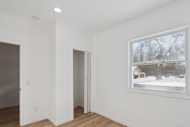 unfurnished bedroom featuring a spacious closet, light hardwood / wood-style flooring, and a closet