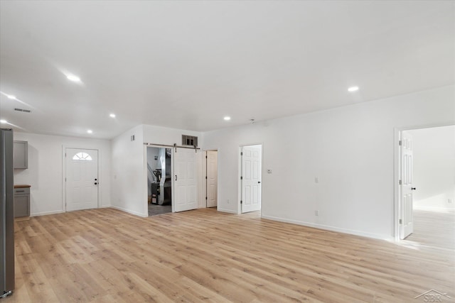 unfurnished living room with light hardwood / wood-style floors and a barn door