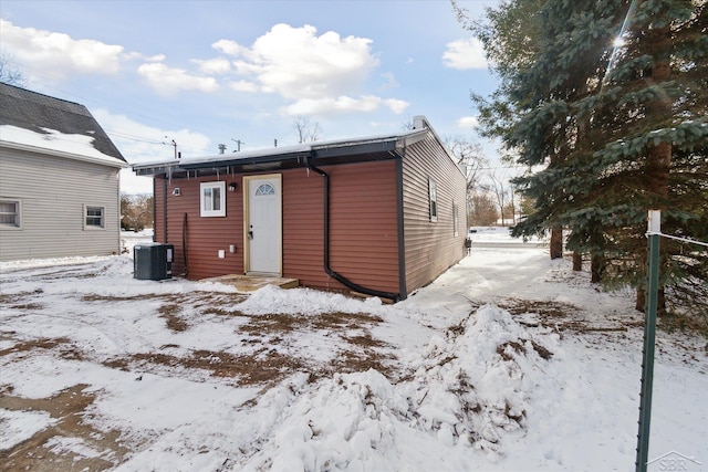 snow covered rear of property featuring central AC