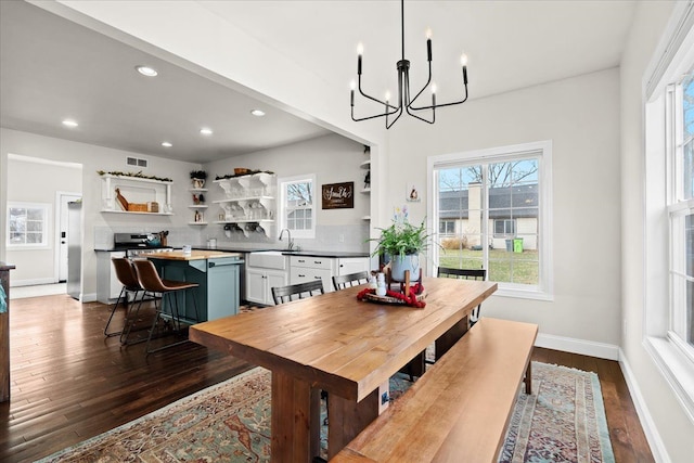 dining room with dark wood-type flooring, an inviting chandelier, and sink