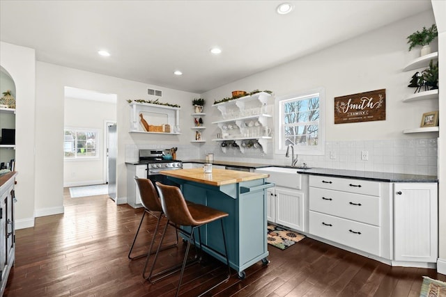 kitchen with wooden counters, a center island, a breakfast bar, sink, and white cabinetry