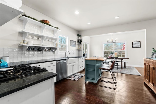 kitchen with dishwasher, gas stovetop, a breakfast bar area, white cabinets, and sink