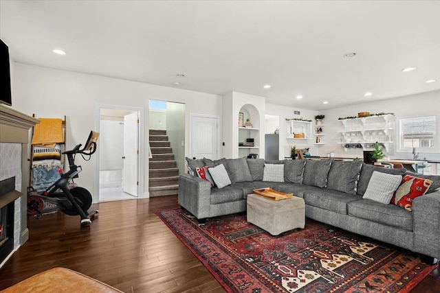 living room featuring a tile fireplace and dark wood-type flooring