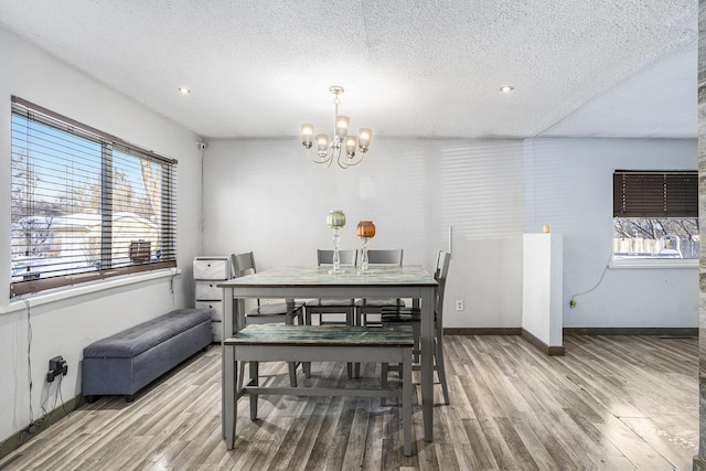 dining room featuring a textured ceiling, an inviting chandelier, and wood-type flooring