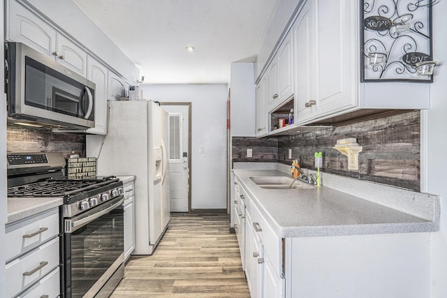 kitchen featuring appliances with stainless steel finishes, white cabinetry, decorative backsplash, and sink