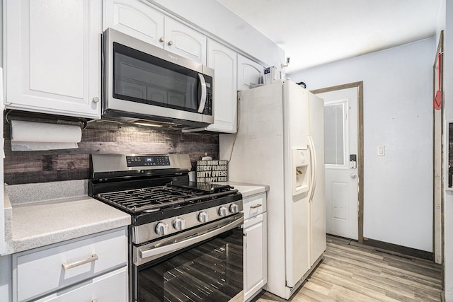 kitchen with light hardwood / wood-style flooring, stainless steel appliances, white cabinetry, and backsplash