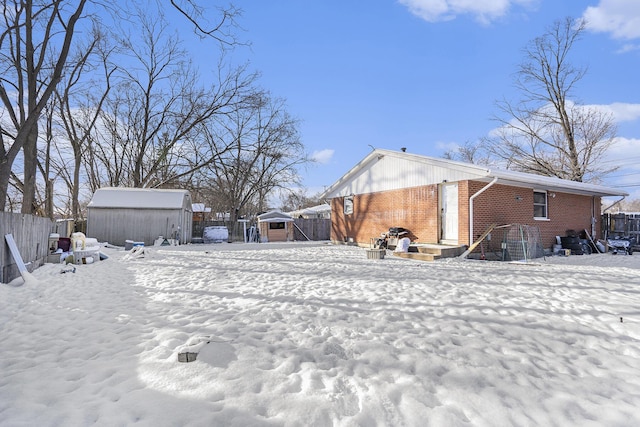 yard covered in snow featuring a storage shed