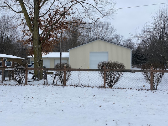 view of snowy exterior featuring a garage and an outdoor structure