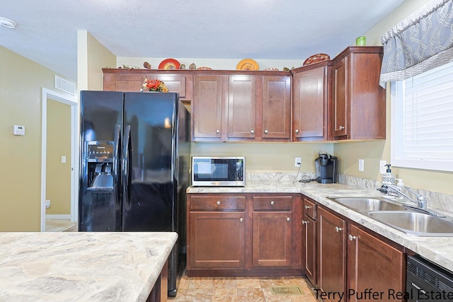 kitchen with a textured ceiling, black appliances, and sink