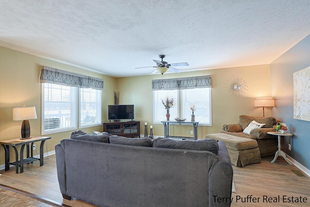 living room with light wood-type flooring, ceiling fan, and a textured ceiling